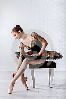 Portrait of young beautiful perfect ballerina sitting on chair indoors