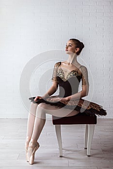 Portrait of young beautiful perfect ballerina sitting on chair indoors