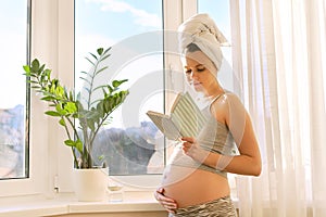 Portrait of young beautiful pregnant woman reading book