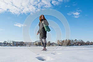 Portrait of a young beautiful red hair european girl walking on snowy frozen river and looking back