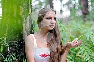 Portrait of a young beautiful Slavic girl with long hair and Slavic ethnic dress in a summer forest