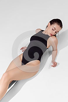 Portrait of young beautiful slim woman in black lingerie, swimming suit posing isolated over gray studio background