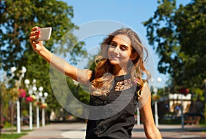 Portrait of young beautiful smiley woman making selfie outdoors