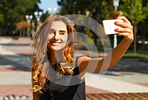 Portrait of young beautiful smiley woman making selfie outdoors