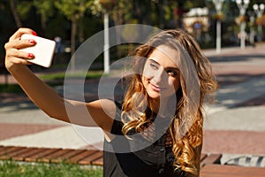 Portrait of young beautiful smiley woman making selfie outdoors