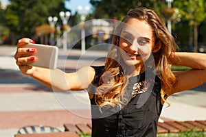 Portrait of young beautiful smiley woman making selfie outdoors