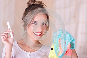 Portrait of young beautiful smiling woman holding a menstruation cotton tampon in one hand and with her other hand an