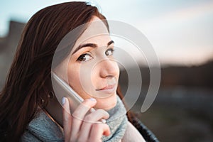 Portrait of young beautiful smilling woman with big eyes calling with cell telephone -  captured from side profile. Brunette