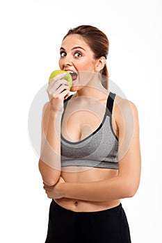 Portrait of young beautiful sportive girl holding apple over white background.