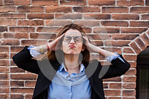 Portrait of young beautiful stressed woman is keeping hands on her head.