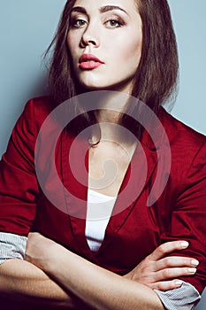 Portrait of young beautiful student girl wearing trendy casual clothing and posing over light blue background with hands crossed.