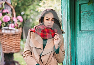 Portrait of a young beautiful stylish brunette woman with long curly hair in a beige coat and scarf