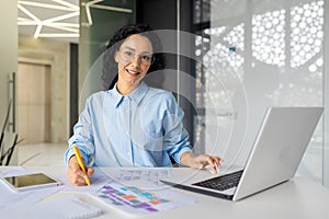 Portrait of young and successful financial accountant at workplace inside office, business woman smiling and