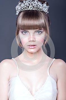 Portrait of young beautiful teenager girl with expressive blue eyes and full parted lips wearing crystal crown looking straight photo