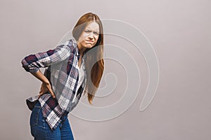 Portrait of young beautiful unhappy woman suffering from backache isolated against grey