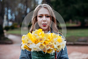 Portrait of a young beautiful woman on autumn background with bouquet of bright yellow flowers. concept of good mood