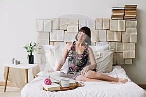 Portrait of a young beautiful woman in bed at home. Beautiful young brunette in the bedroom. Good morning. Lifestyle.