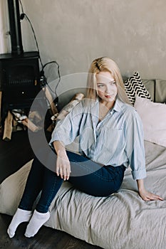 Portrait of a young beautiful woman in bed in the morning at home. Blonde girl in scandinavian interior. Good morning. Lifestyle.