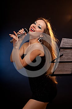 Portrait of a young beautiful woman in black dress singing