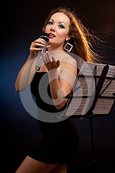 Portrait of a young beautiful woman in black dress singing