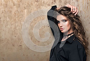 Portrait of young beautiful woman in black shirt posing in front of a metal wall