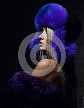 Portrait of young beautiful woman in blue purple fashion arctic fox winter fur ear flap hat