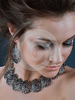 Portrait of young beautiful woman with brown hair fresh skin wearing accessories and jewelry isolated over dark blue background
