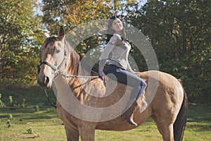 A Portrait of young beautiful woman with brown horse outdoors