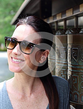 Portrait of young beautiful woman with buddhist praying cylinders of Kodaiji temple on background, Kyoto, Japan