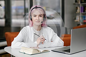 Portrait of young beautiful woman, business woman smiling and looking at camera, receptionist using headset for video call, happy