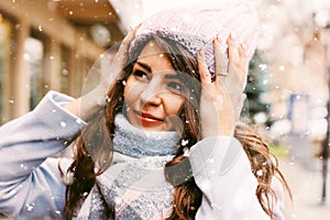 Portrait of young beautiful woman in coat and hat enjoing first snow