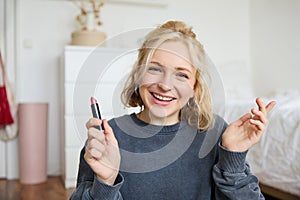 Portrait of young beautiful woman, content maker creating a new vlog, beauty video, showing lipstick, recommending