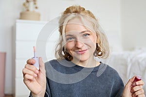 Portrait of young beautiful woman, content maker creating a new vlog, beauty video, showing lipstick, recommending