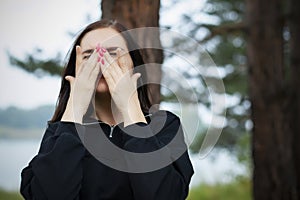 Portrait of young beautiful woman crying in park in nature. concept of breaking up with your husband or boyfriend