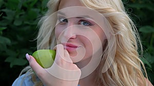 Portrait of a young beautiful woman with curly blond hair against a park. Beautiful face, blue eyes and luscious lips