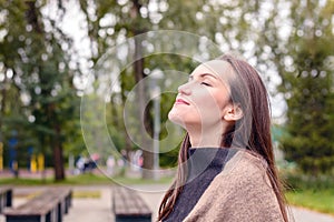 Portrait of young beautiful woman doing breath of fresh autumn air in a green Park. the concept of pure atmospheric air, the envir