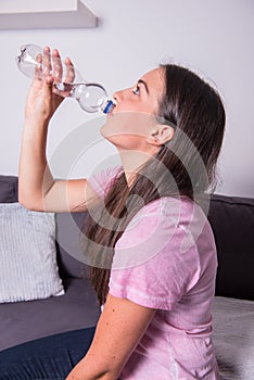 Portrait of a young beautiful woman drinking water out of the bo