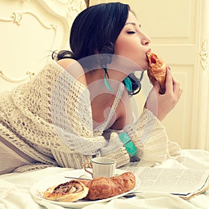 Portrait of a young beautiful woman eating her croissant with st