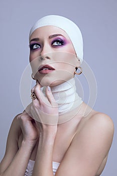 Portrait of young beautiful woman in elegant hair accessories, bandage, golden earrings with bright makeup posing on