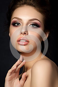 Portrait of young beautiful woman with evening make up touching