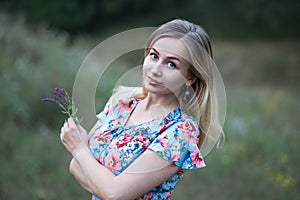 Portrait of young beautiful woman in flower vintage dress holding flowers in her hands