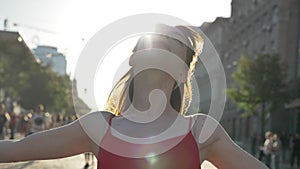 Portrait of young beautiful woman with ginger hair standing on street, lifting head, touching hair and smiling, people