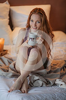 Portrait of young beautiful woman her hands holding cup of coffee morning cold winter time in her white bedroom. Happy