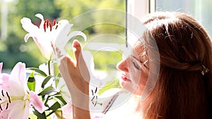 Portrait of a young beautiful woman with lily. The girl smells the scent of flowers