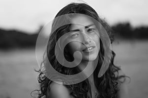 Portrait of a young beautiful woman with long curly hair at the seaside
