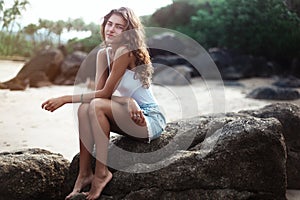 Portrait of a young beautiful woman with long curly hair at the seaside