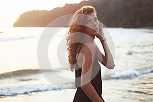 Portrait of a young beautiful woman with long curly hair at the seaside