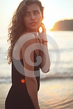 Portrait of a young beautiful woman with long curly hair at the seaside