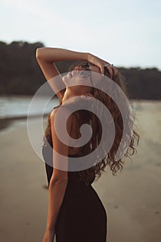 Portrait of a young beautiful woman with long curly hair at the seaside