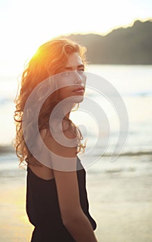 Portrait of a young beautiful woman with long curly hair at the seaside